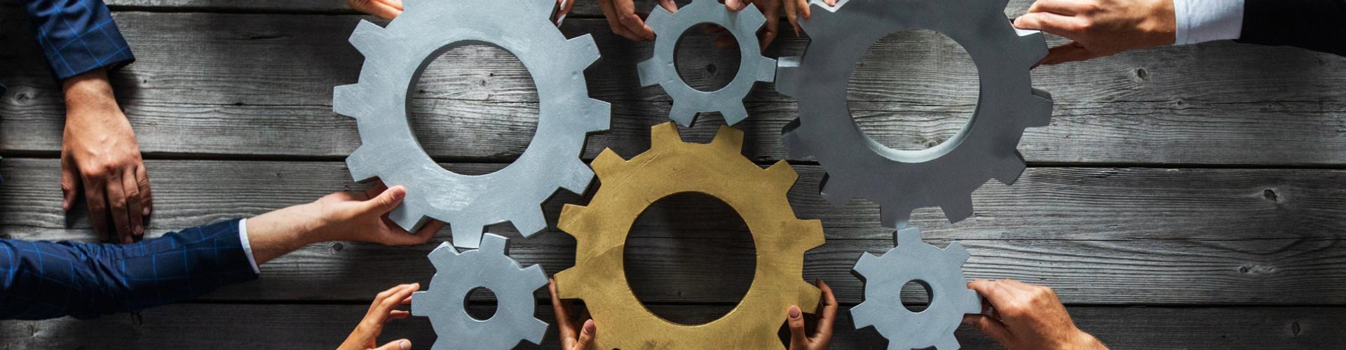 Différents engrenages avec des mains de plusieurs personnes