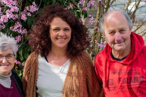 Trois personnes posent dans un jardin