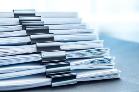 Plusieurs dossiers papier tenus avec des pinces